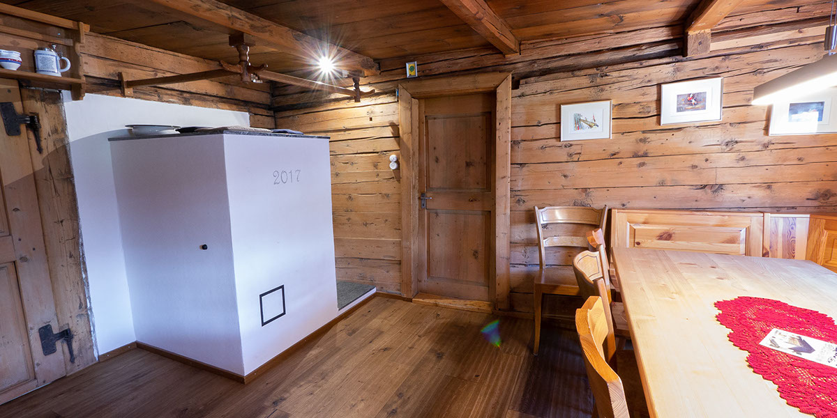 Bildbeschreibung: Wohnraum, gemütliche Stube mit viel Altholz und Kachelofen, Maiensässromantik.