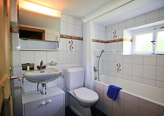 Bildbeschreibung: weiss gekachelte Wände, Lavabo, WC und Bad vom Ferienhaus Tgiasa Cao.