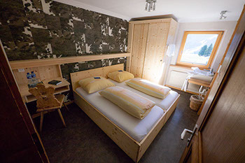 Bildbeschreibung: rustikales Hotelzimmer mit Kuhfellen an der Wand im Berghotel Sartons, Valbella.
