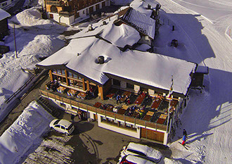 Bildbeschreibung: Luftaufnahme vom Berghotel Restaurant Sartons mit Terrasse und Schnee.