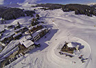 Bildbeschreibung: winterliche Luftaufnahme des Berghotel Restaurants Sartons, umgeben von Schnee und Piste.
